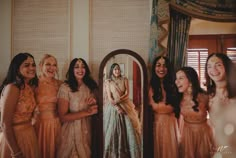 a group of women standing next to each other in front of a mirror and smiling