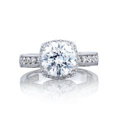 an engagement ring with diamonds on the band and a center stone surrounded by two rows of pave