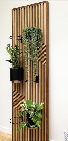 three potted plants are hanging on a wooden paneled wall with black metal brackets