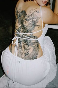 a woman with tattoos on her back sitting in a chair