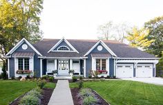 a blue and white house with two garages on the front porch, landscaping around it