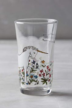 a clear glass with an image of a horse and flowers painted on the side, sitting on a table