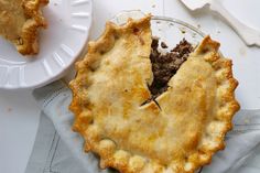 a pie sitting on top of a white plate next to a fork and spoons