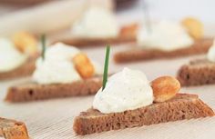 small pieces of bread topped with whipped cream and green toothpicks on a table