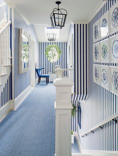 a hallway with blue and white striped wallpaper on the walls next to a stair case