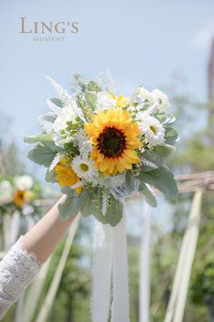 a bride's bouquet with sunflowers and greenery