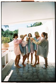 a group of women standing next to each other in front of a white wall holding towels