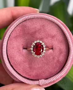 a pink velvet ring with a red stone in the center and white diamonds around it