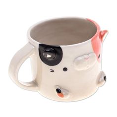 a ceramic mug with a cat design on the front and side of it's face