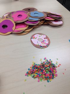 a table topped with lots of doughnuts and sprinkles next to a pile of donuts