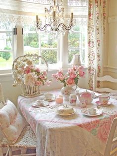 there is a table with pink flowers on it and two chairs in front of the table