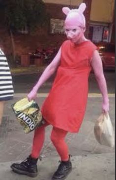 a woman in pink bunny ears is walking down the street with her handbag and purse