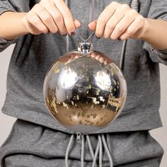 a person holding onto a shiny ball ornament