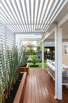 an outdoor patio with wooden flooring and white pergolated covering over the area