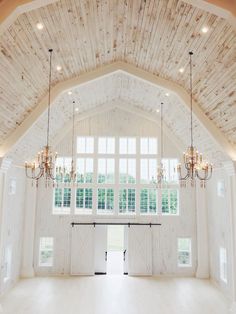 a large open room with chandeliers and windows in the ceiling is decorated with wood planks