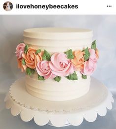 there is a white cake with pink and orange flowers on the top, along with green leaves