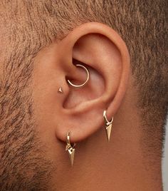 a man wearing gold ear piercings with two small spikes