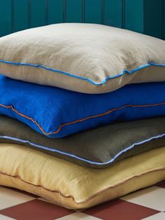 three pillows stacked on top of each other in front of a blue wall and checkered floor