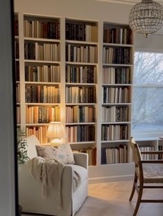 a living room filled with furniture and lots of bookshelves next to a window