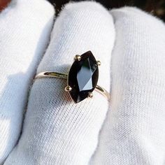 a woman's hand holding a ring with a large black stone in the middle