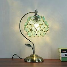 a table lamp sitting on top of a wooden desk next to a box and book