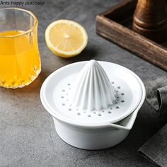 a white grater sitting on top of a table next to a glass of orange juice