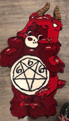 a red rug with a demon head and pentagram on it, sitting next to a pair of black shoes