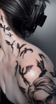 the back of a woman's neck with black ink tattoos on her body and headphones