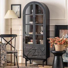 a black china cabinet sitting in the corner of a living room next to a table