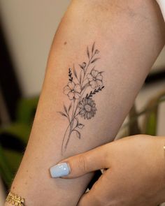 a woman's arm with flowers on it and a small tattoo on the left side of her arm