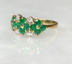 Emerald Flower Ring, Emerald Ring For Women, Emerald Ring Vintage, Natural Emerald Ring, Emerald Dainty Ring, Emerald Solid 18k Gold Ring A delightful vintage solid 18k gold floral ring featuring 12 lively green round emeralds weighing 0.75 carats forming 3 flowers side by side while accented by 4 sparkling white diamonds weighing 0.15 carats. *Ring size: US 7 1/2 * Complimentary resizing is available up to 3 sizes larger or smaller than stated size. Fine Jewelry Flower-shaped Multi-stone Rings, Diamond Multi-stone Flower Ring, Flower Shaped Diamond Ring With Multi-stones, Yellow Gold Flower-shaped Multi-stone Rings, Yellow Gold Flower-shaped Rings With Multi-stone, Yellow Gold Floral Multi-stone Rings, Formal Green Flower-shaped Ring, Emerald Ring Designs For Women, Emerald Ring Design