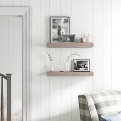 a living room filled with furniture and decor on top of white wooden wall shelves next to a stair case