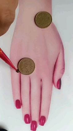 a woman's hand with two gold coins on it and a red manicure