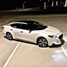 a white car parked in a parking lot at night