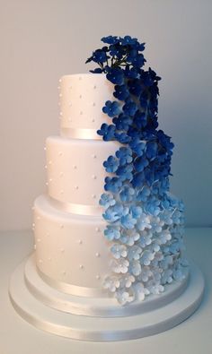 a three tiered white cake with blue flowers on top