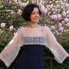 a woman standing in front of a tree with pink flowers