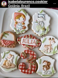 decorated cookies are arranged in the shape of numbers and animals on a plate with name tags