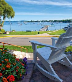 a white lawn chair sitting on top of a brick patio next to a body of water