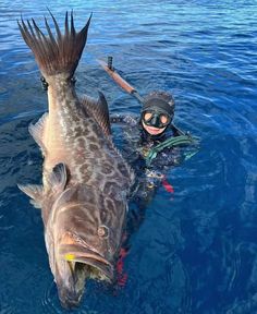 a man is in the water with a large fish on his back and a scuba mask