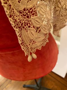 the back of a red chair with lace on it