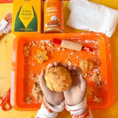 a person holding a cookie in front of an orange tray