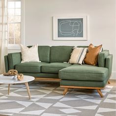 a living room with green couches and pillows on the floor next to a coffee table