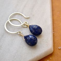 Our Midnight Earrings are cobalt blue with dainty gold inclusions - like the dark sacred night sky with stars twinkling. These Lapis Lazuli earrings feature faceted gemstones in an inky dark blue hue with golden striations. We hand wire-wrap the gemstones in our signature tightrope style, anchored beneath our classic lure earwires. Available in affordable Gold Fill, Sterling Silver, and Rose Gold Fill; or heirloom-quality solid 14K Gold (Yellow, Rose, or White Gold). Our high quality sustainable Nickel Free 14k Gold-filled Blue Jewelry, Nickel-free 14k Gold-filled Blue Jewelry, Blue Teardrop 14k Gold Filled Jewelry, Blue 14k Gold-filled Nickel-free Jewelry, Blue 14k Gold Filled Nickel-free Jewelry, Teardrop Lapis Lazuli Earrings For Gift, Lapis Lazuli Teardrop Earrings For Gifts, Lapis Lazuli Teardrop Earrings As Gift, Nickel Free Blue Briolette Jewelry