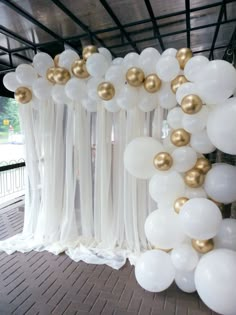 white and gold balloons are hanging from the ceiling