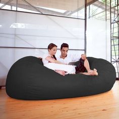 a man and woman sitting on a bean bag chair in the middle of a room