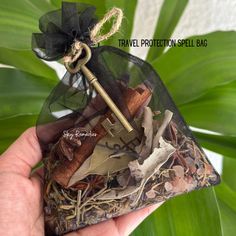 a hand holding a bag filled with lots of stuff next to a leafy plant