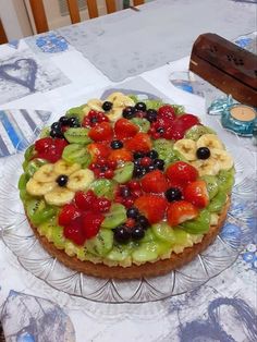 a fruit tart on a glass plate sitting on a table