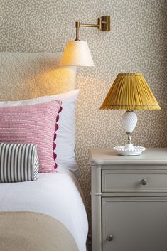 a bedroom with two lamps on either side of the bed and a nightstand next to it