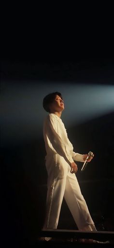 a man standing on top of a stage with a microphone in his hand and lights behind him