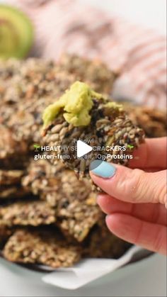 a woman is holding up an oatmeal cookie with avocado on top